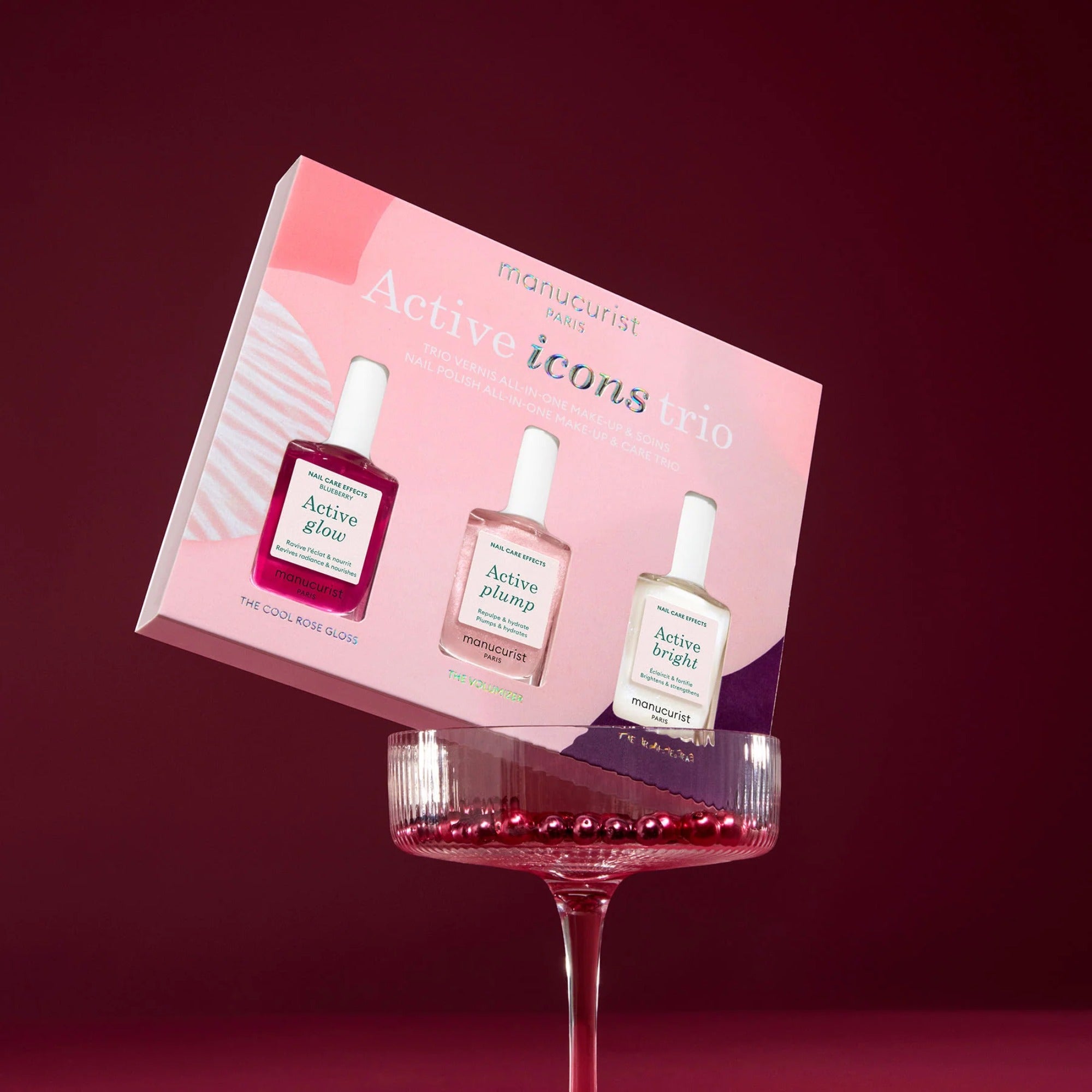 Manucurist Active Icons Trio nail polish gift set displayed in a glass with red background.