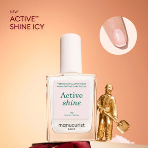 A bottle from the Manucurist Advent Calendar Time to Shine! collection is displayed alongside a gold figurine holding a shovel, echoing the thrill of uncovering festive treasures. An inset circle highlights a close-up of a fingernail adorned with shimmering polish—an ideal choice for elevating your holiday nail and hand care routine.