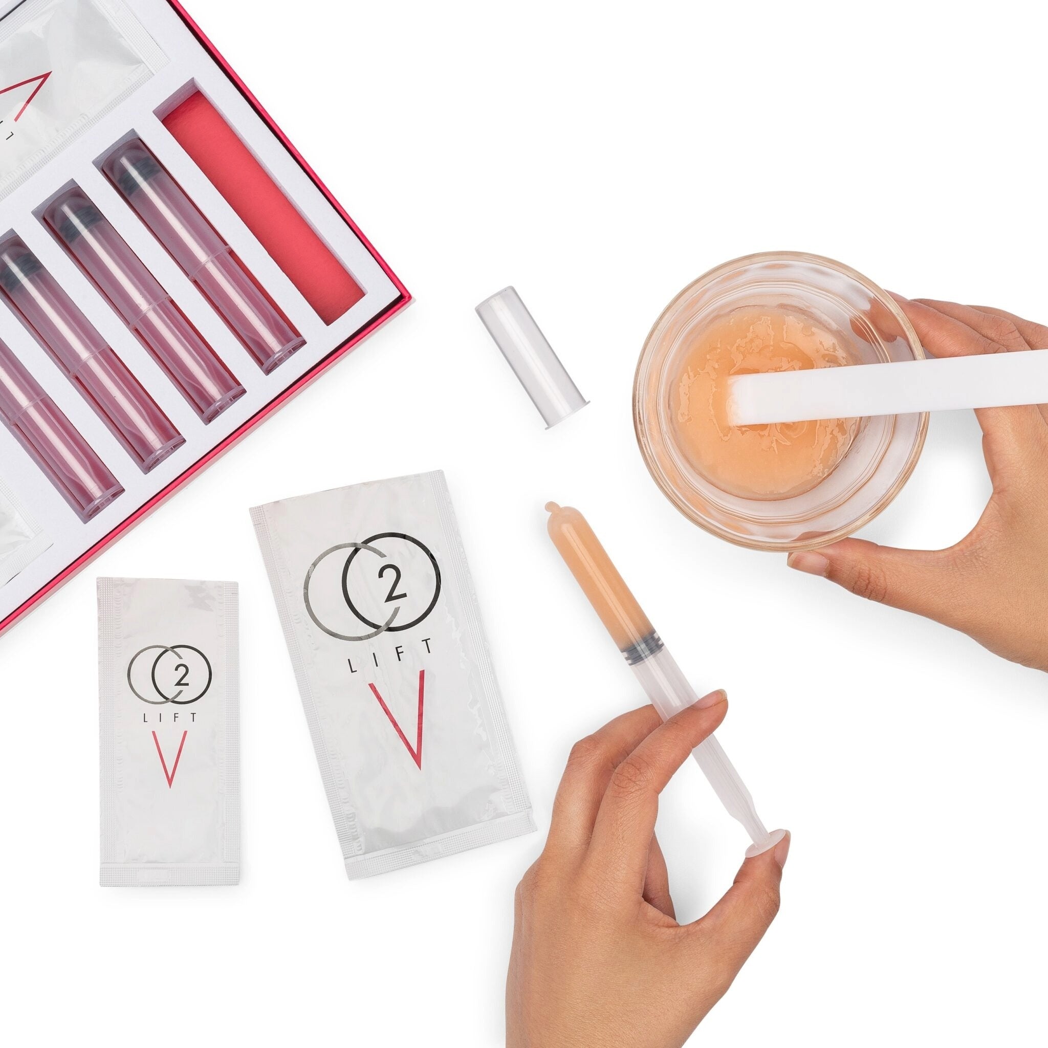 Hands mixing CO2Lift V vaginal rejuvenation gel from Lumisque using included syringe and sachets, showing the preparation process of the treatment kit.